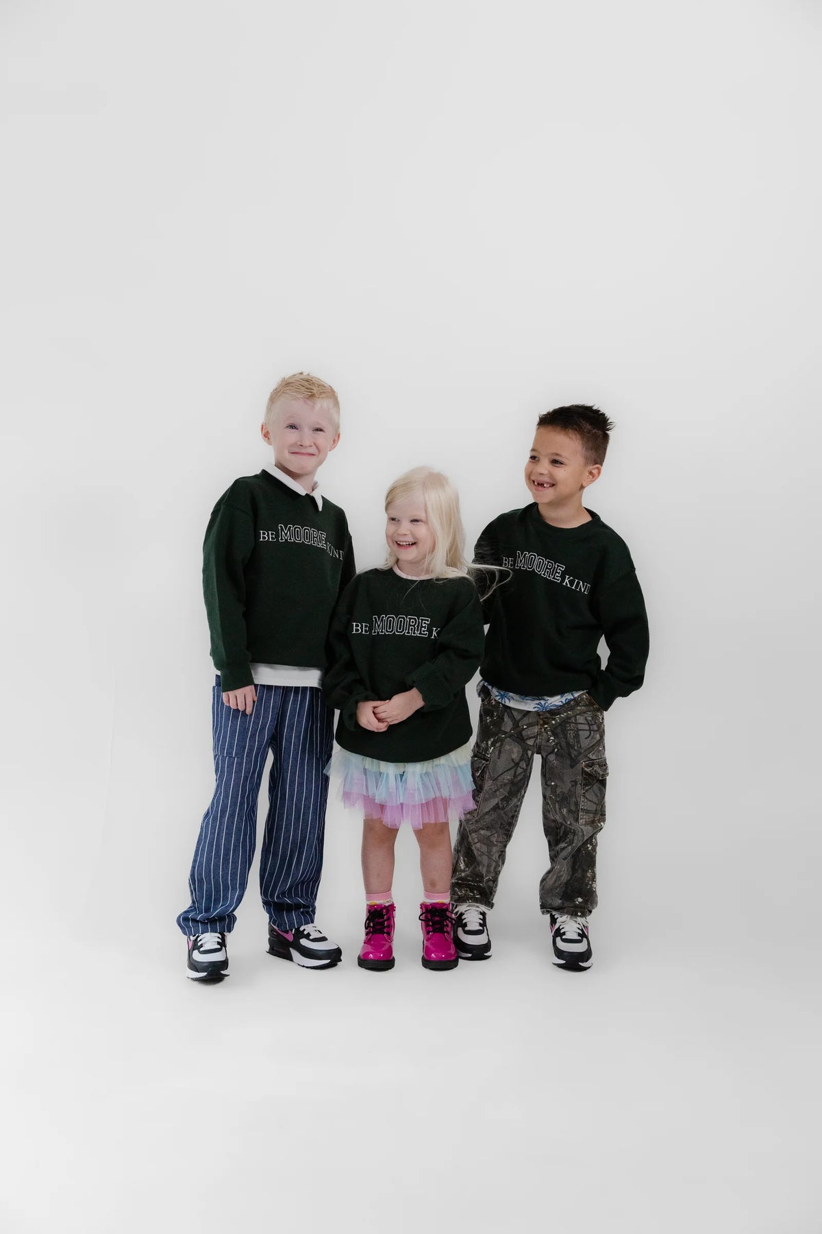Three kids in green Be Moore Kind fleeces